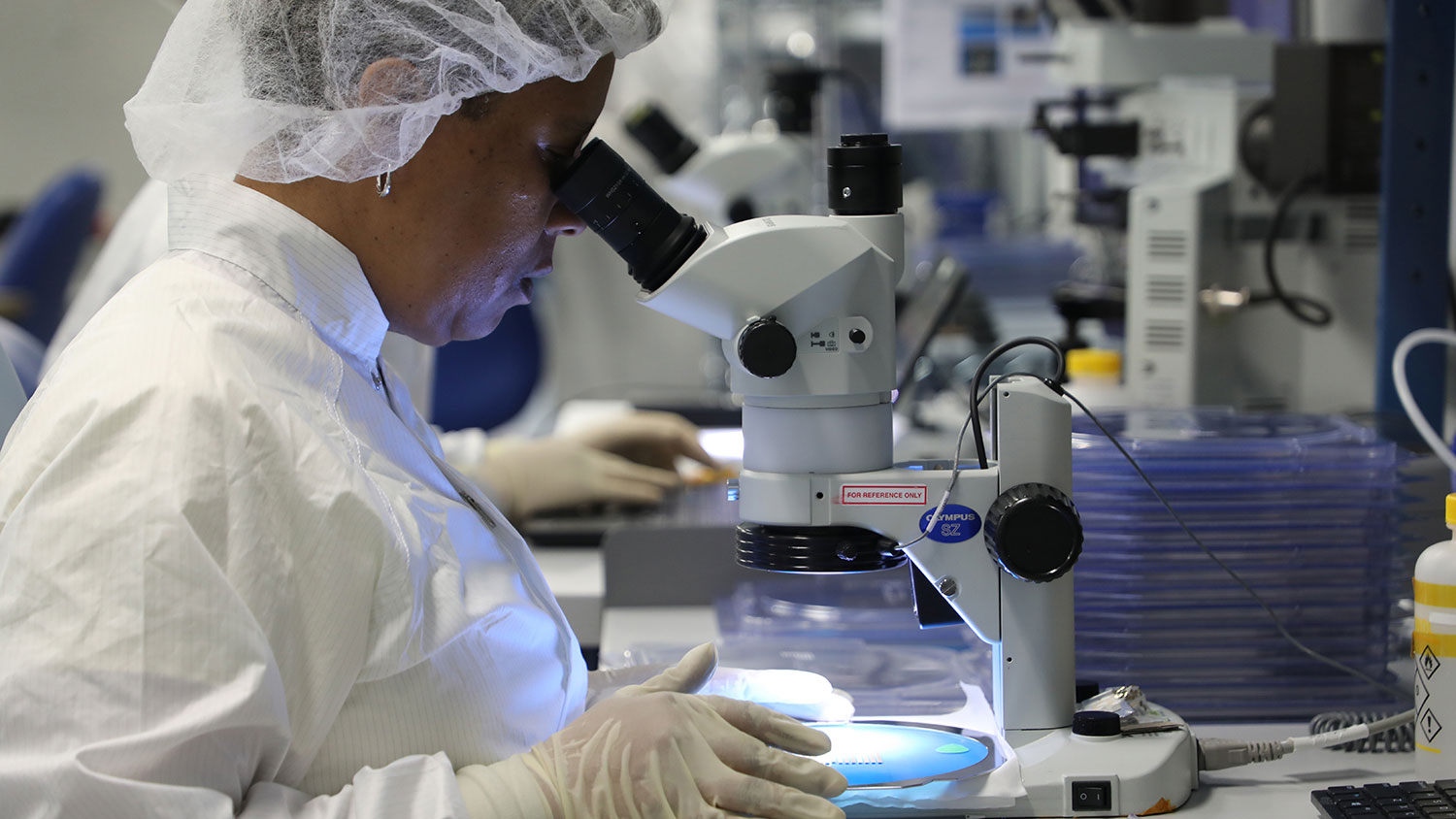 Phononic employee looks through a microscope.