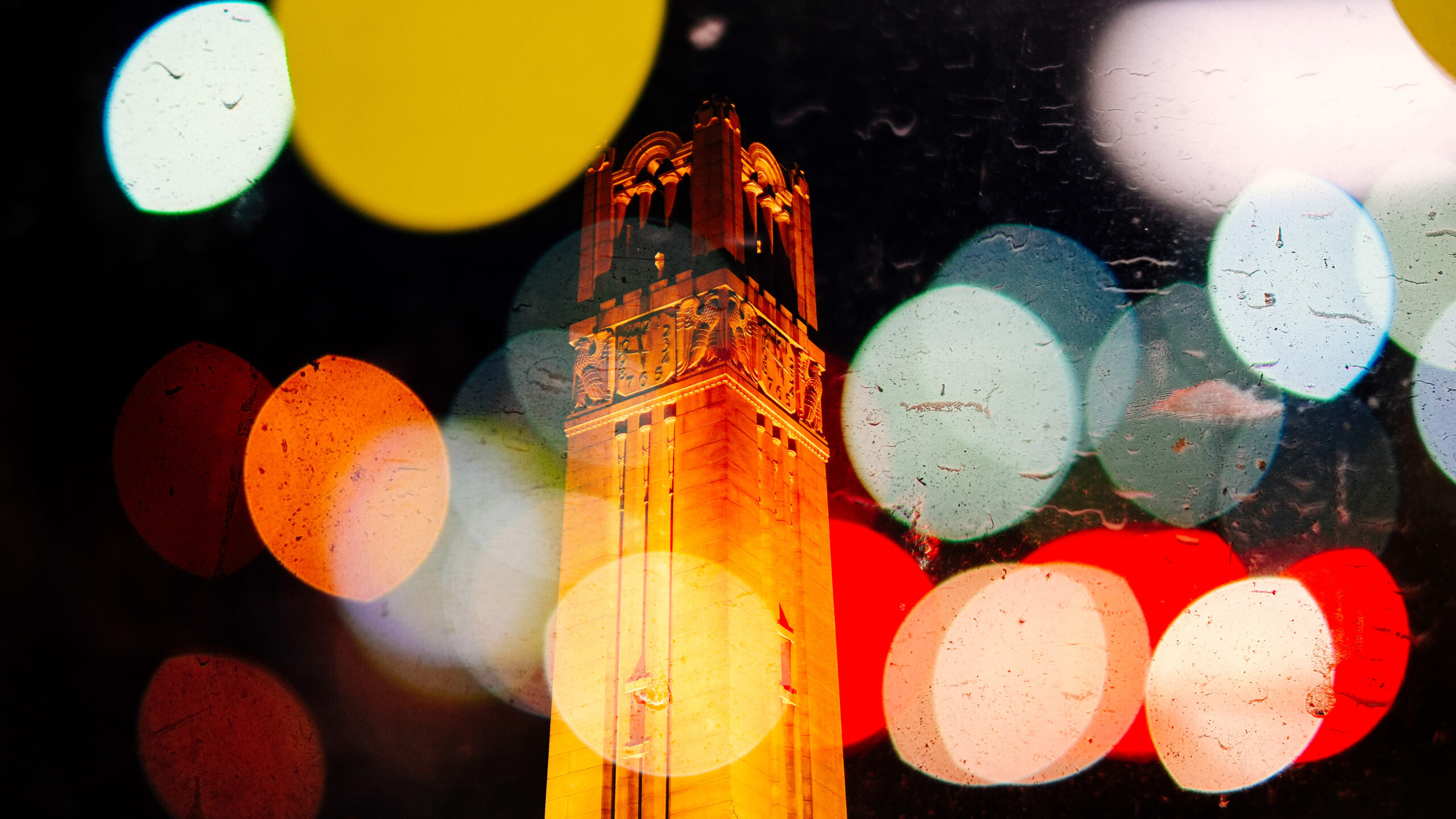 The NC State Belltower lit at night.