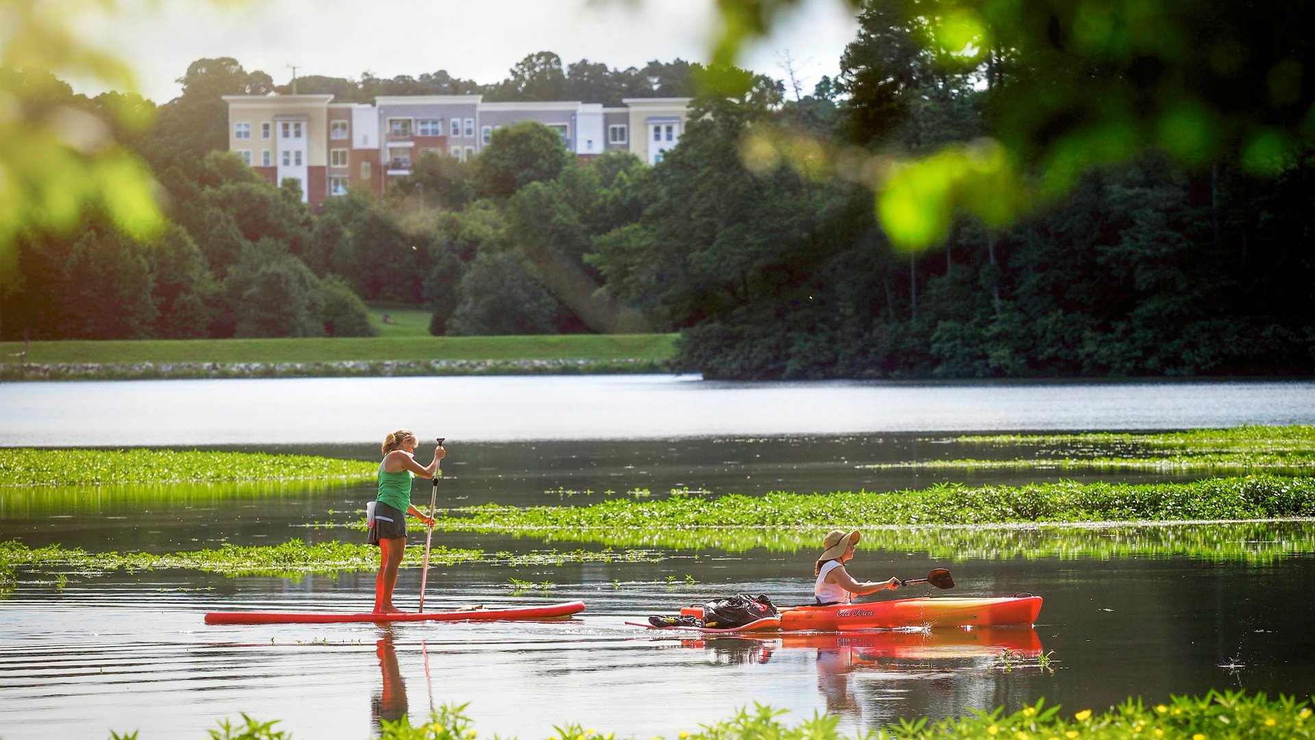 Two women kayak and paddleboard on Lake Raleigh.