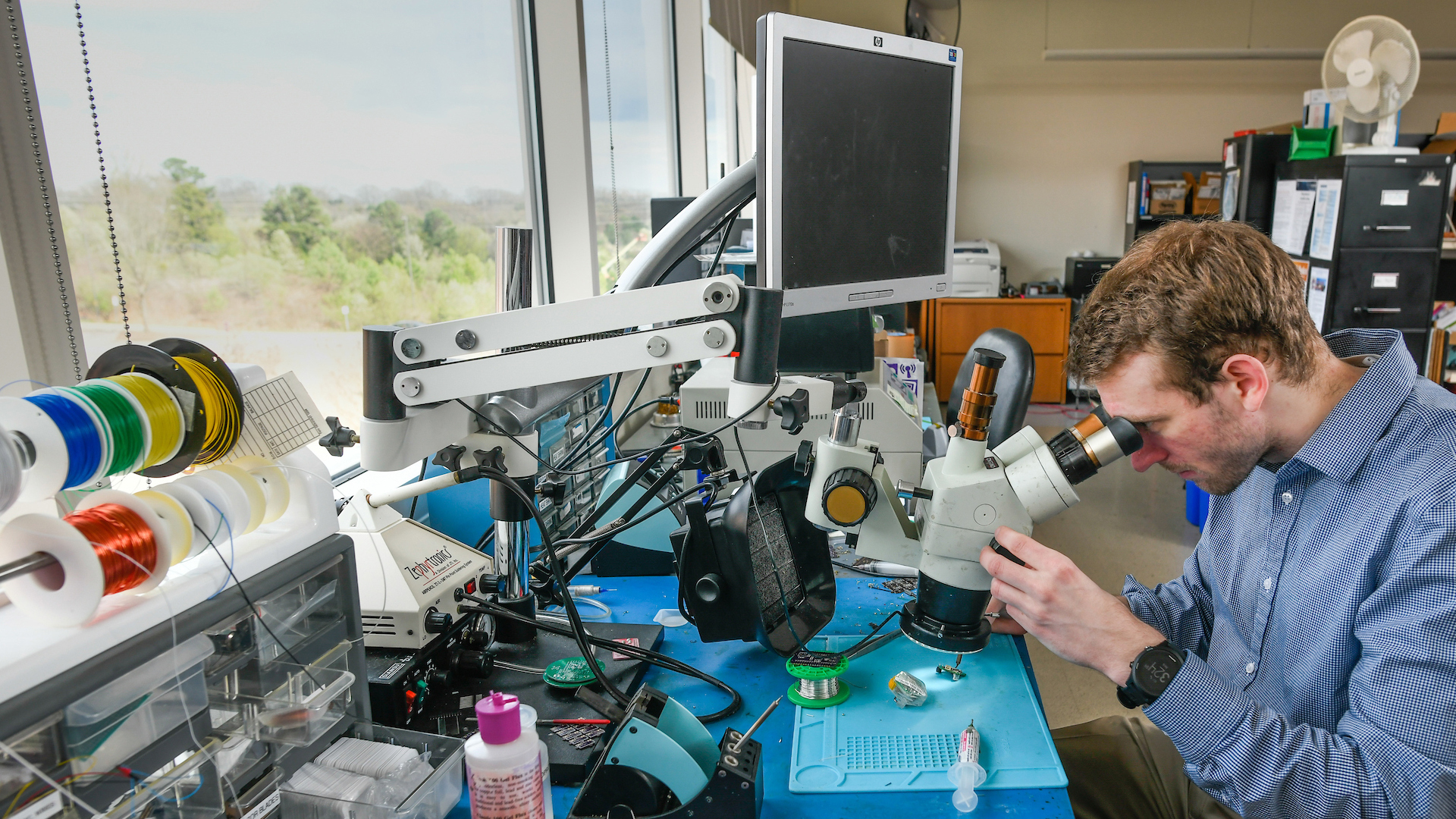 A researcher examines material under a microscope in a lab on NC State's Centennial Campus.