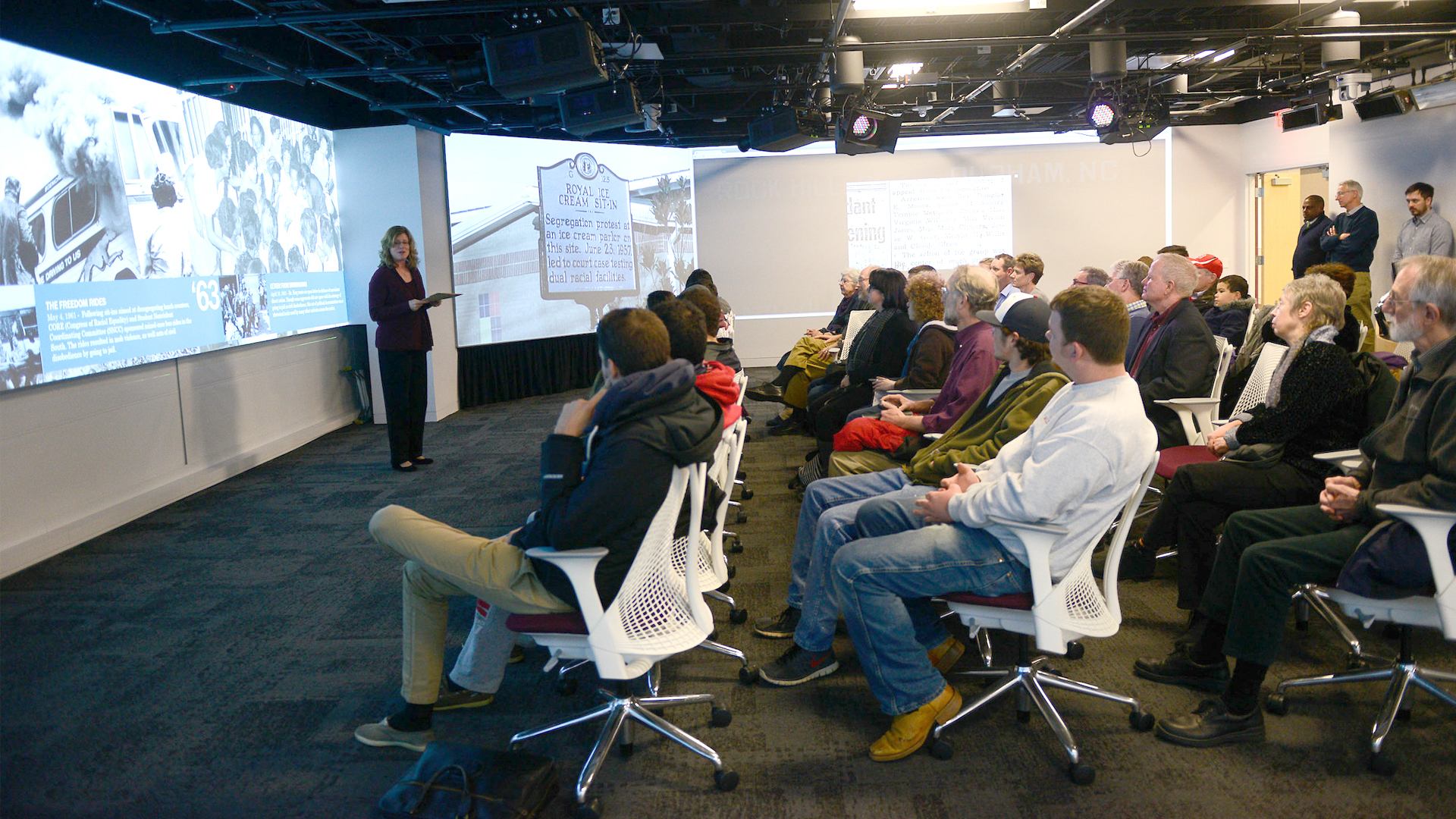 Working professionals hold a meeting in the visualization lab in Hunt Library.