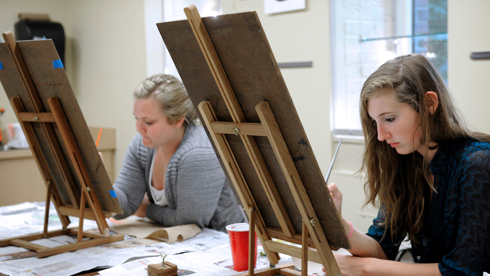 Young adults paint at easels during a course at the NC State Crafts Center.