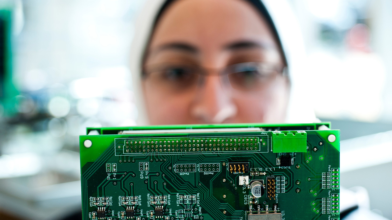 A woman examines a large block of electrical chips.