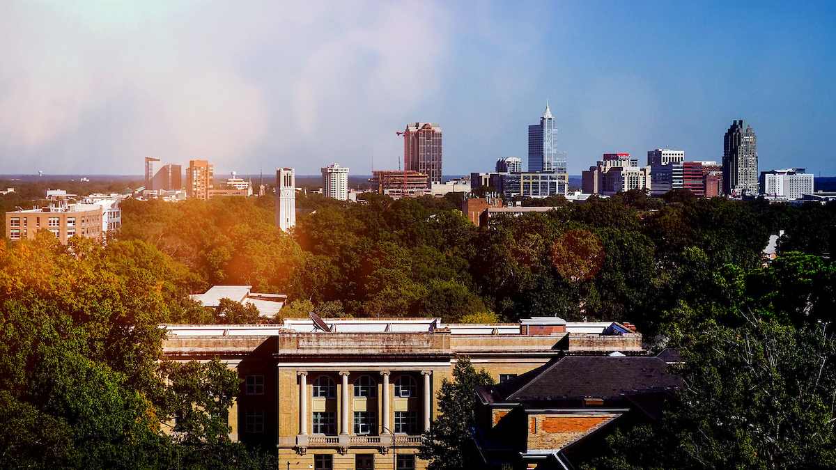 Ricks Hall (in the foreground) and the Belltower on NC State's campus, with downtown Raleigh behind.